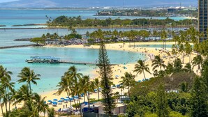 A beach with palm trees, a pier, and a view of the ocean and mountains. - Ocean View Penthouse Suite, Steps to Beach, Sleeps 6! (Honolulu)