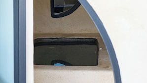 A curved staircase with a beige wall and a black frame at the top. - Anaktos Cave Houses (Santorini)