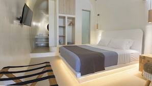 A modern bedroom with a bed, a TV mounted on the wall, and a built-in wardrobe. - Anaktos Cave Houses (Santorini)