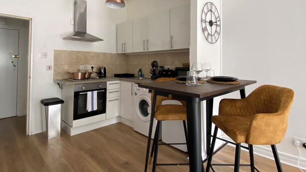 Una cocina moderna con una isla central, electrodomésticos de acero inoxidable y una lámpara colgante.