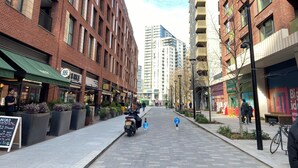 A street lined with brick buildings, some with balconies, and a clear sky.