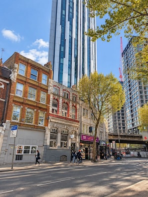A street with a mix of modern and traditional buildings, a clear sky, and pedestrians.