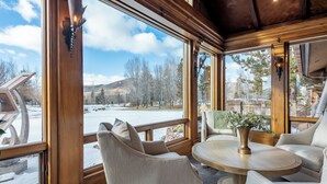 Une pièce chaleureuse avec de grandes fenêtres, une table ronde en bois et des sièges confortables.
