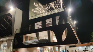 A hotel with a modern design, featuring a prominent sign with illuminated letters, a glass facade, and a spacious interior with visible seating areas. - Hotel Annapurna (Ratlam)