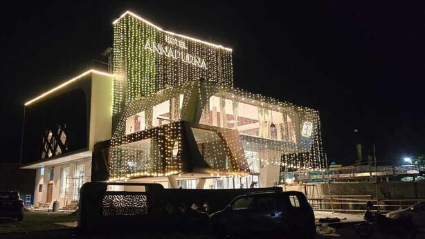 A hotel with a modern design, featuring a prominent sign and decorative lighting. - Hotel Annapurna (Ratlam)