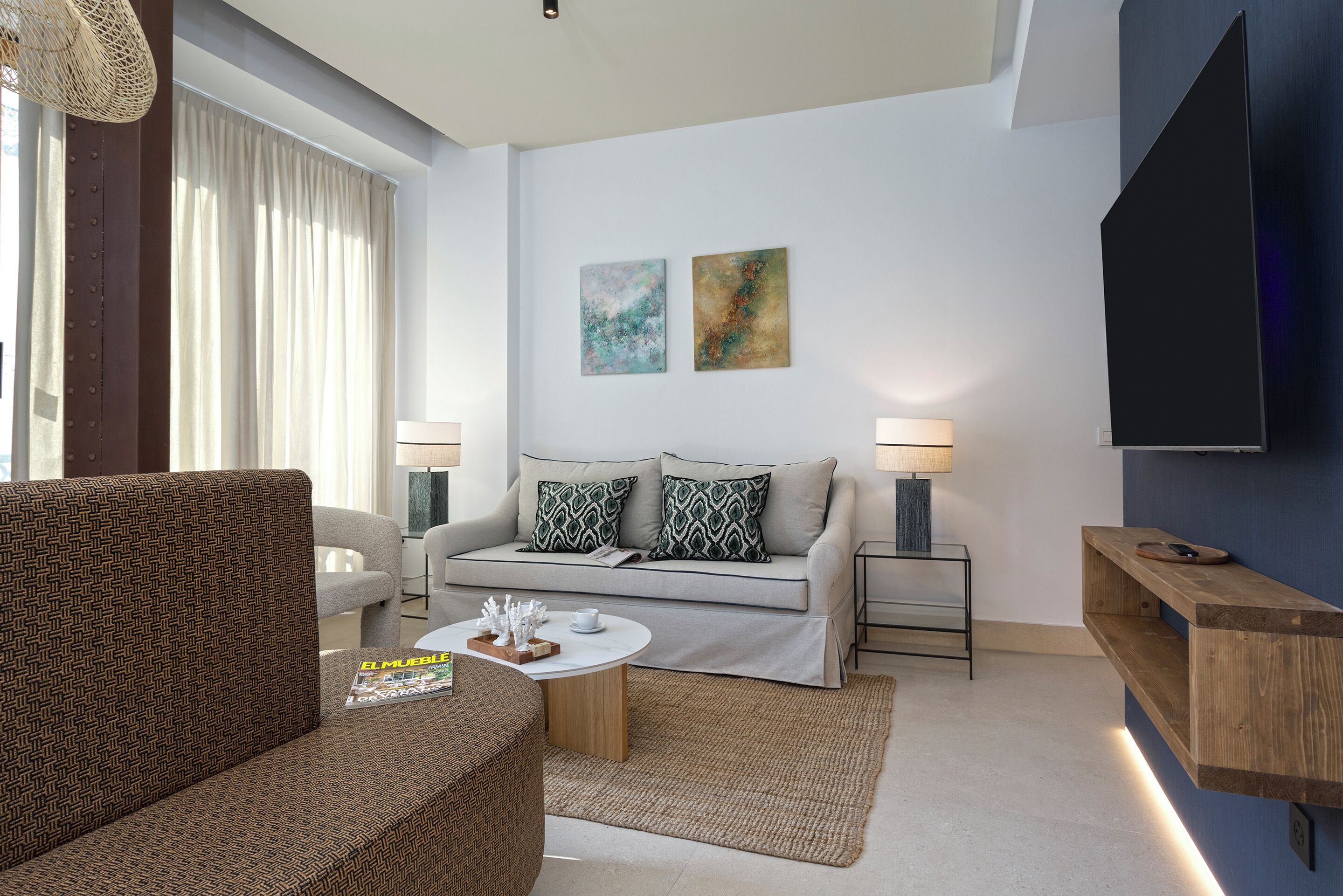Una sala de estar moderna con un sofá, una mesa de centro y un televisor montado en la pared.