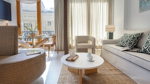 A modern living room with a round coffee table, a sofa, a chair, and a dining table with chairs. - Genteel Home Tomás de Ibarra 15 (Seville)