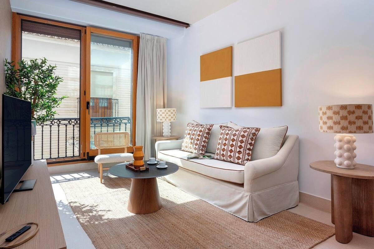 A modern living room with a sofa, coffee table, TV, and a balcony with a view.