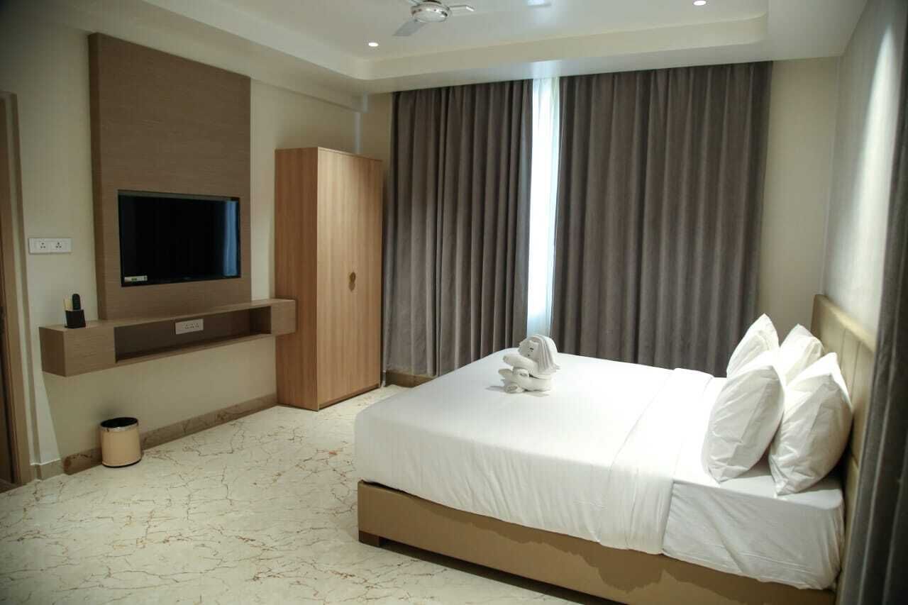 Una habitación de hotel con una cama grande, un televisor en la pared y un armario.