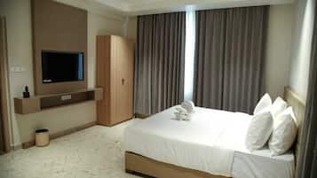 Una habitación de hotel con una cama grande, un televisor en la pared y un armario.