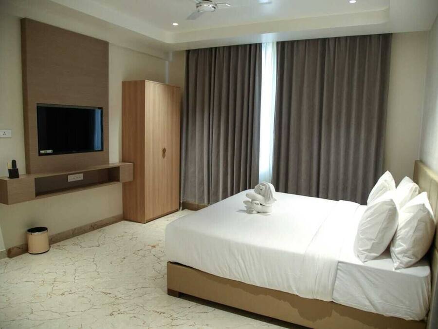 Una habitación de hotel con una cama grande, un televisor en la pared y un armario.