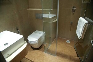 A bathroom with a toilet, a glass shower enclosure, and a sink.