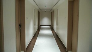 A long, narrow hallway with doors on both sides, leading to rooms. - LEAF HOTEL (Tiruvannamalai)