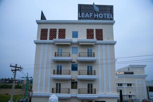 A hotel with a sign reading "Leaf Hotel" and a smaller sign for "Palace" in the background.