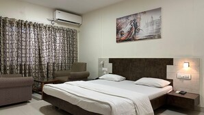 A modern bedroom with a large bed, a chair, a painting, and an air conditioning unit. - FARM REGENCY GORAI (Mumbai)