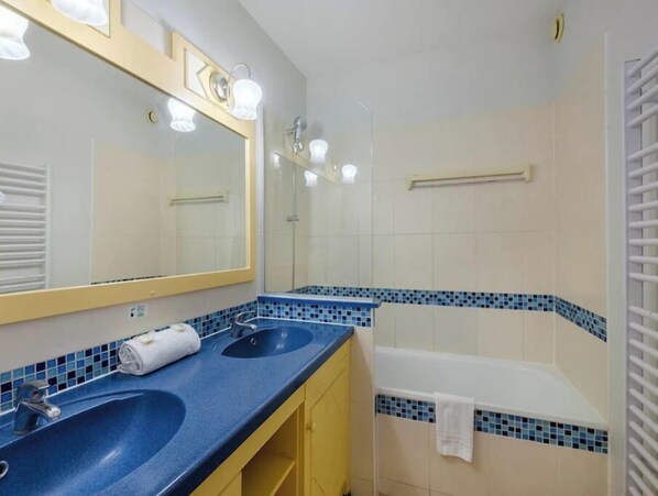 Une salle de bain avec deux lavabos, un miroir, une douche et un porte-serviettes.