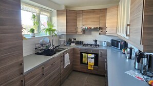 Una cocina moderna con armarios de madera, microondas integrado y cafetera.