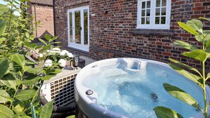 A brick building with a hot tub in front, surrounded by greenery. - Egerton Cottage (Crewe)