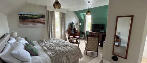 A bedroom with a bed, a desk, a chair, a television, and a mirror.
