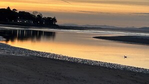 Une rivière paisible au coucher du soleil, avec une plage de sable et un petit bateau.