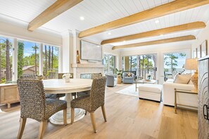 A spacious living area with a large round table, wicker chairs, a white sofa, and a balcony with a view of trees. - Oceanfront, All New! 3rd Floor, 2BR/2 BA, Updated, Open Plan & Super Stylish (Hilton Head Island)