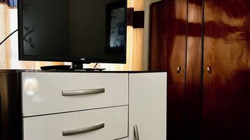 Un televisor sobre un mueble con cajones y un armario de madera.