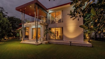 Una casa moderna de dos pisos con un porche cubierto, ventanas amplias y un césped bien cuidado.