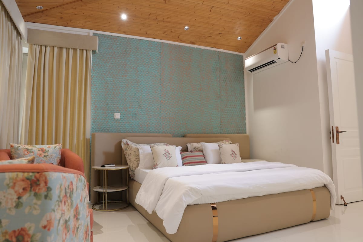 A bedroom with a bed, a round side table, a small round table, and a door.