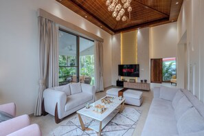 A modern living room with a large sofa, a coffee table, and a flat-screen TV mounted on the wall. - Sukoon A Family Villa (Rishikesh)