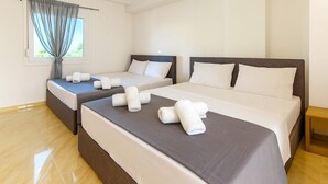 A hotel room with two beds, a large window with curtains, and a wooden floor. - Aigli Garden Retreat, Cozy Escape Close to the Sea (Volvi)