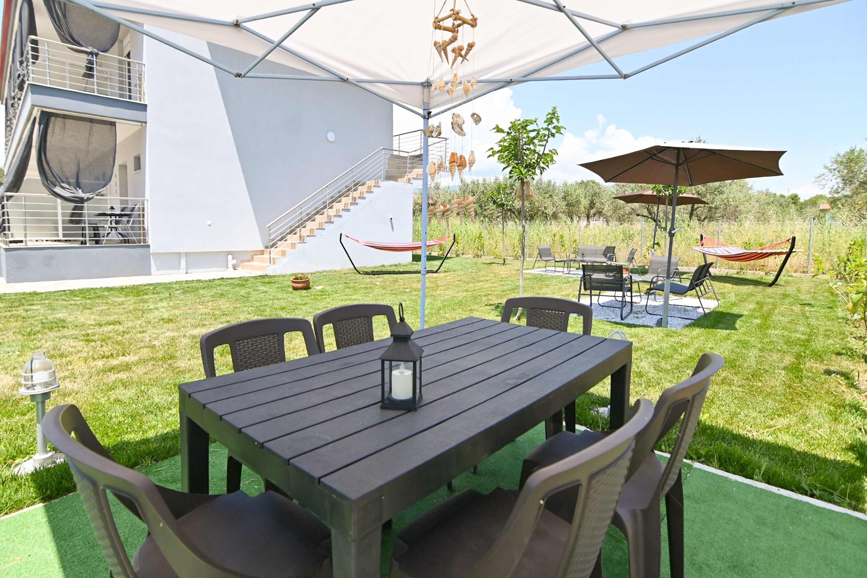 An outdoor patio with a wooden table and chairs, surrounded by green artificial turf.