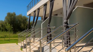 A modern building with a balcony, metal railings, and a staircase leading to an upper level. - Aigli Garden Retreat, Cozy Escape Close to the Sea (Volvi)