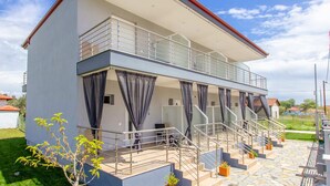 A two-story house with a balcony, a staircase, and a garden area. - Aigli Garden Retreat, Cozy Escape Close to the Sea (Volvi)