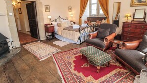 A traditional bedroom with a bed, two chairs, a dresser, and a fireplace. - Catherine Parrs Sewing Room (Bedale)