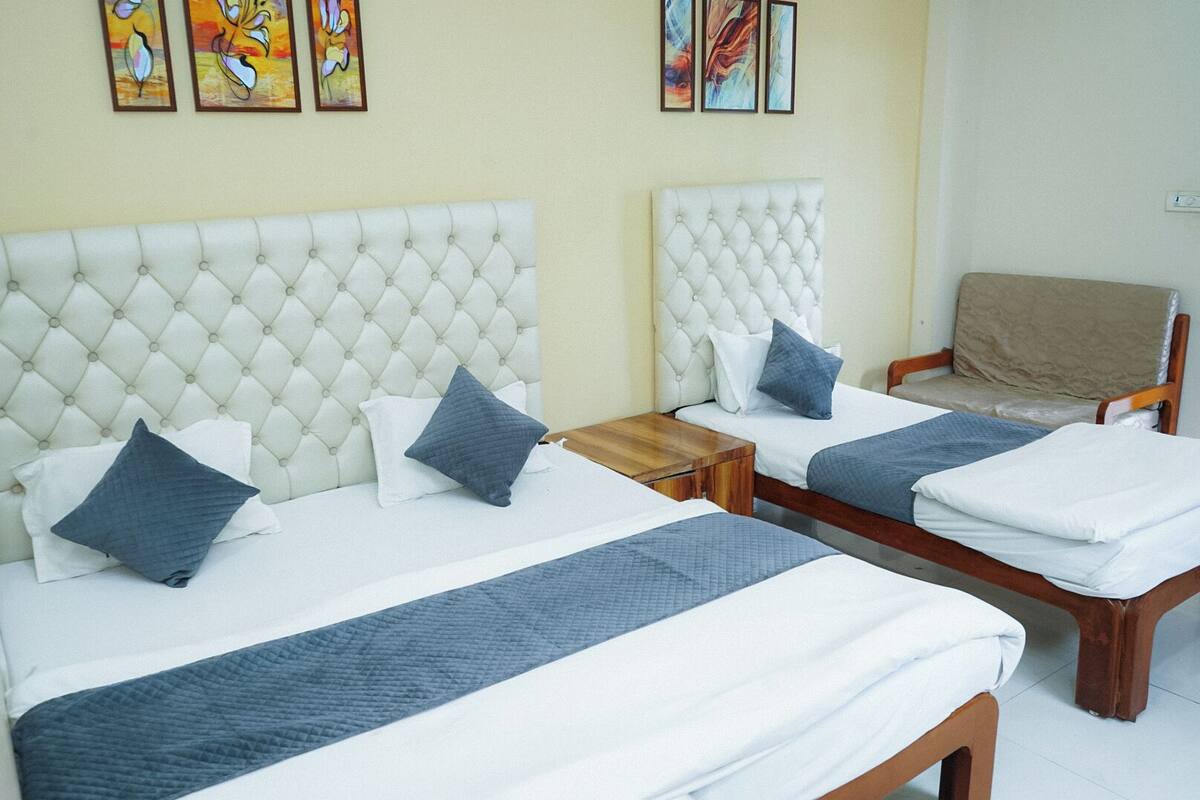 A hotel room with two beds, each with a tufted headboard, a wooden nightstand, and a chair.