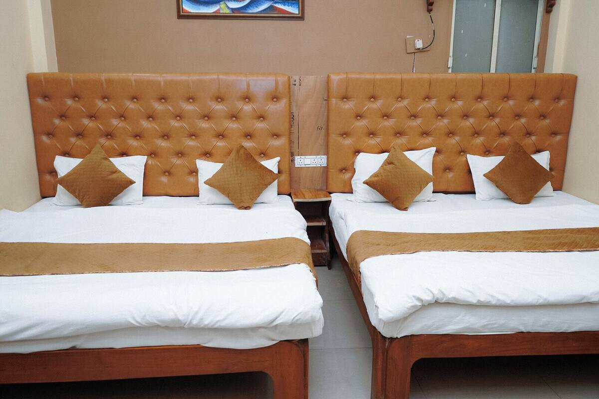 Two twin beds with brown headboards and white bedding, arranged in a room with a tiled floor and a wooden nightstand between them.
