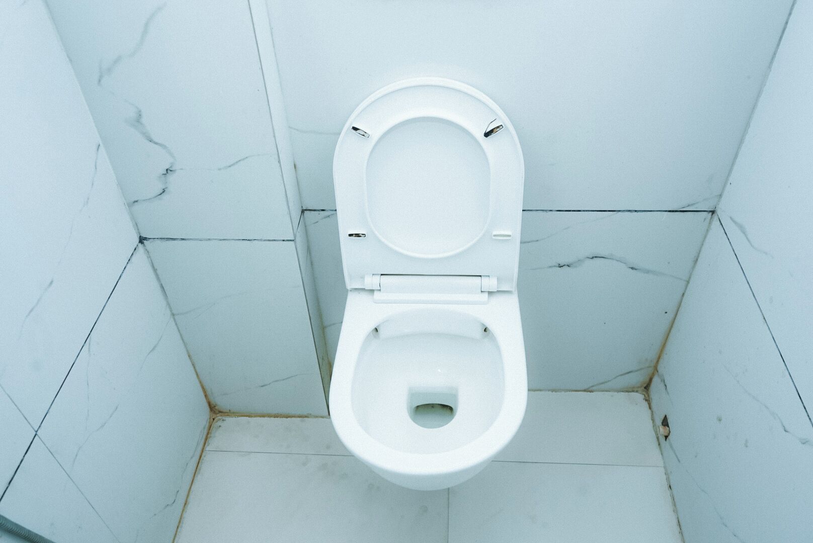 Des toilettes blanches dans une salle de bain carrelée de marbre blanc.