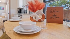 A dining table with a white bowl, a glass, and a sign that reads "Welcome NEXTGEN STAYS". - Casa Corazón - Walk to UA (Tucson)