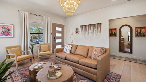 A living room with a brown sofa, two armchairs, a round coffee table, and a chandelier. - Casa Corazón - Walk to UA (Tucson)