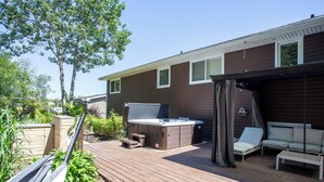 En terrass med ett bubbelbad, utomhusmöbler och en pergola.