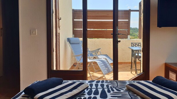 Ein Zimmer mit einer Schiebeglastür, die zu einem Außenbereich mit Pool, Liegestühlen und einem Tisch führt.