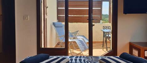 A room with a sliding glass door leading to an outdoor area with a pool, lounge chairs, and a table.