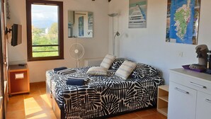 Ein Schlafzimmer mit Bett, Ventilator, Karte und Blick ins Freie.