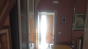 A narrow hallway with a tiled floor leading to a room with a yellow table and chairs.