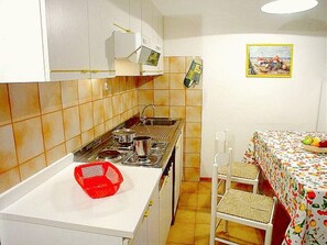 Eine kleine Küche mit Herd, Spüle und einem Essbereich mit Tisch und Stühlen.