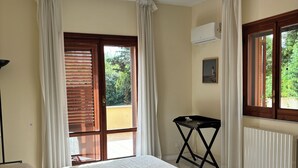 Quarto com cama, radiador, janela com cortinas e uma pequena mesa.