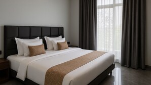 A modern hotel room with a large bed, dark headboard, and a view of the city through sheer curtains. - Inn Of Joy (Noida)