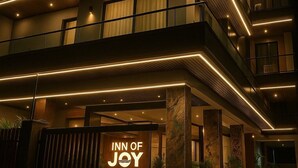 A multi-story hotel with a prominent "INN OF JOY" sign at the entrance. - Inn Of Joy (Noida)