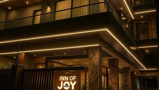 A multi-story hotel with a prominent "INN OF JOY" sign at the entrance. - Inn Of Joy (Noida)