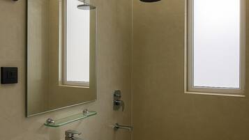 Un baño moderno con tocador, espejo, ducha y ventilador de techo.